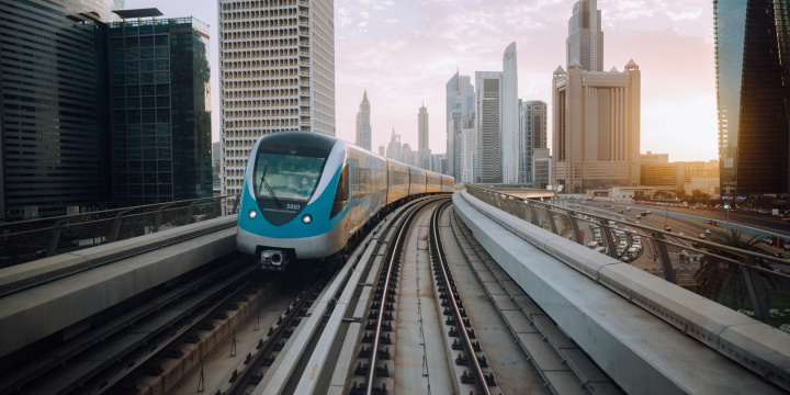 Een metro rijdt door een moderne stad heen, met de skyline van de stad op de achtergrond